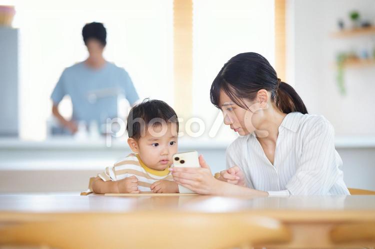 母の持つスマホに釘付けの子供 親子,スマートフォン,持つの写真素材