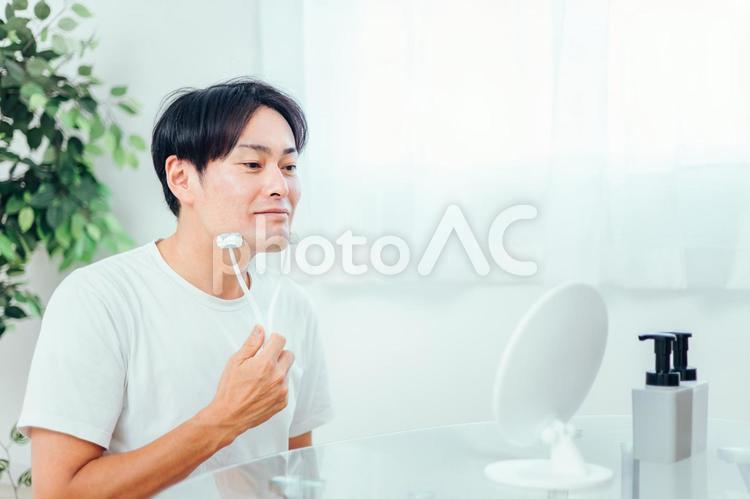 美顔ローラーを使う男性（笑顔） 美顔ローラー,顔痩せ,むくみの写真素材