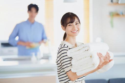 畳んだタオルを運ぶ笑顔の女性 女性,タオル,持つの写真素材