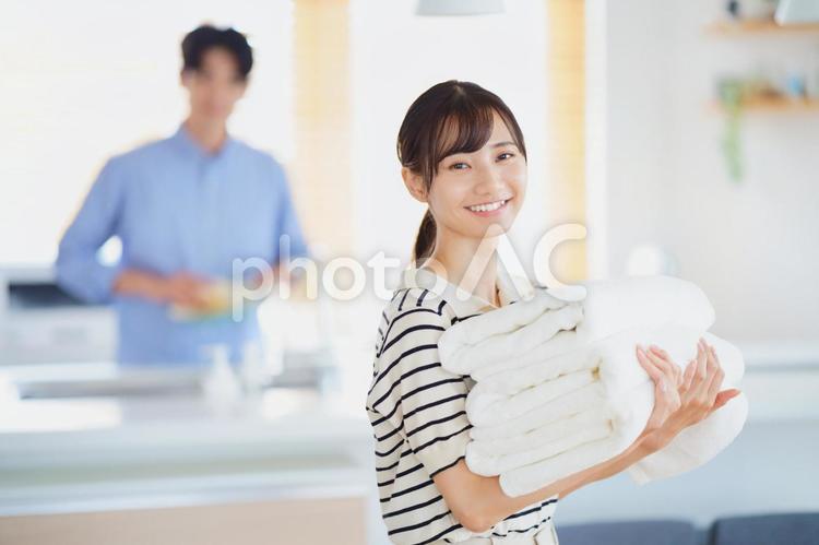 畳んだタオルを運ぶ笑顔の女性 女性,タオル,持つの写真素材