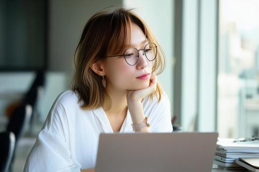PCを前に悩むビジネス女性 PCを前に悩むビジネス女性の写真