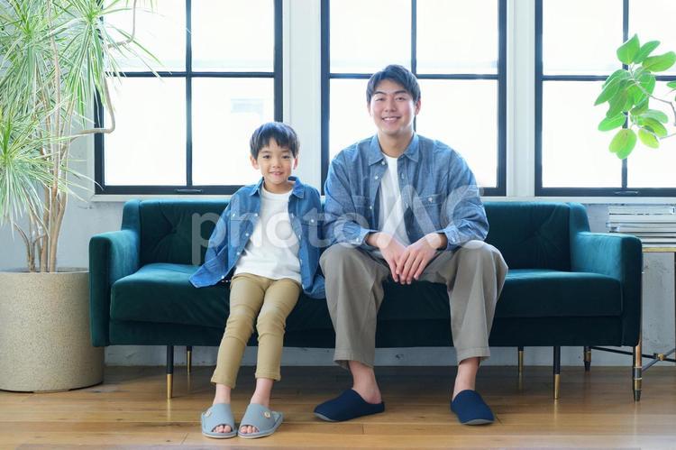 カメラ目線でソファーに座っている親子 親子,男の子,小学生の写真素材
