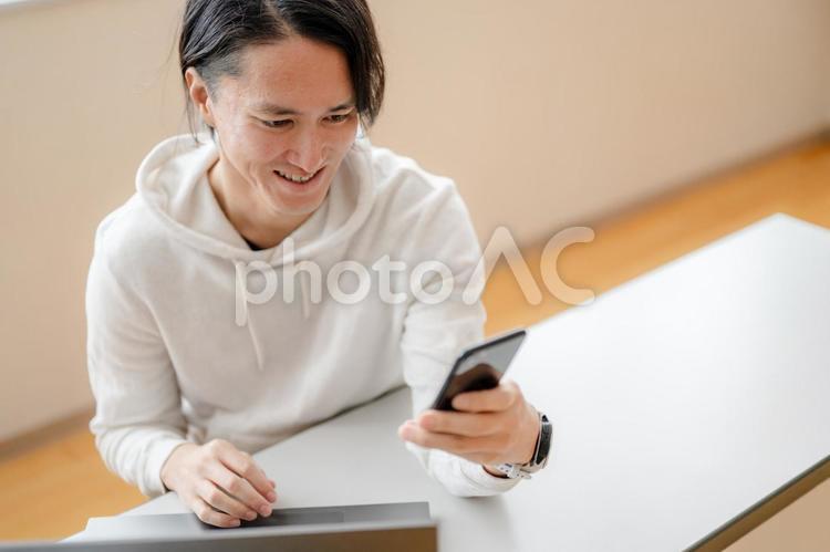 スマホを操作するPC男性 男性,日本人,若者の写真素材