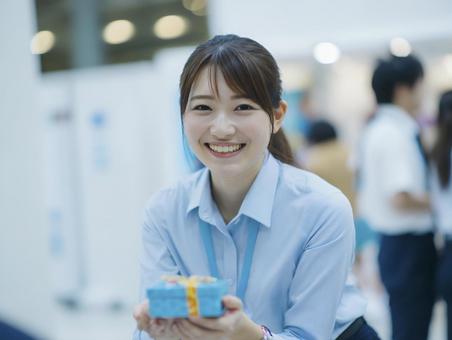 プレゼントを差し出すシャツ姿の女性 プレゼントを差し出すシャツ姿の女性の写真