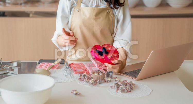 ハートのチョコを持つエプロン姿の女性 バレンタイン,バレンタインデー,チョコの写真素材