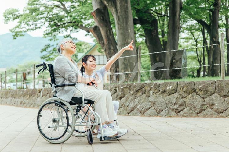 車椅子に乗った高齢者女性と女性スタッフ（全身） 介護,老人ホーム,看護師の写真素材