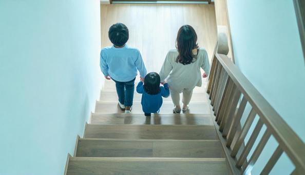 階段を上るのが楽しい子供と見守る両親の写真