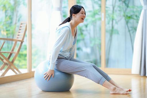 バランスボールを押さえて座る女性 女性,バランスボール,押さえるの写真素材