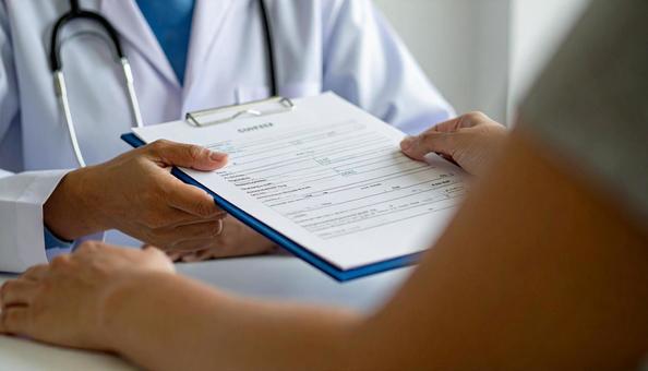 手術前に患者に手術同意書を渡す医師 手術前に患者に手術同意書を渡す医師の写真