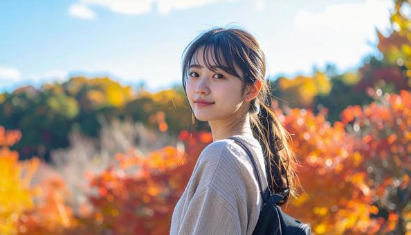 紅葉を背景に振り返り微笑む若い女性 紅葉を背景に振り返り微笑む若い女性の写真
