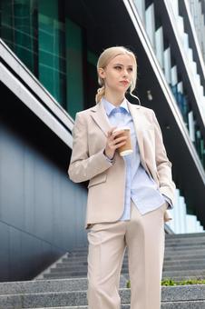 オフィスビルの外でコーヒーを持って立っているビジネスウーマン ビジネスウーマン,ビジネス,女性の写真素材
