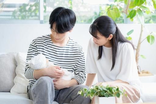 リビングで赤ちゃんを抱く若い家族 リビングで赤ちゃんを抱く若い家族 家族,親子,赤ちゃんの写真素材