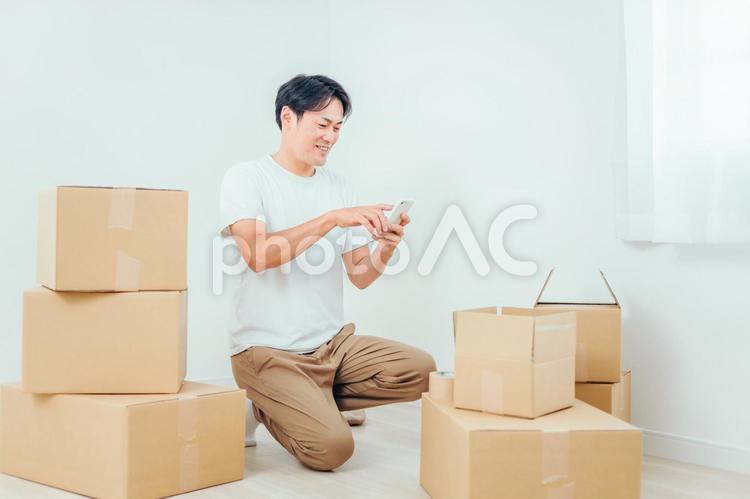 ダンボールとスマホを使う男性 引越し,スマホ,荷造りの写真素材