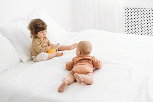 ベッドの上で見つめ合う子供たち ベッドの上で見つめ合う子供たち 赤ちゃん,かわいい,ベッドの写真素材