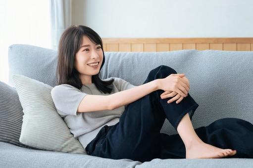 リビングのソファに座る笑顔の女性 リビングのソファに座る笑顔の女性 女性,ソファ,微笑むの写真素材