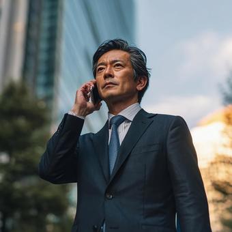 都会で電話する真剣な表情のビジネスマン 都会で電話する真剣な表情のビジネスマンの写真