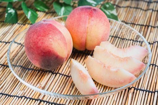 Cut peaches arranged on a bamboo blind and glass plate, JPG