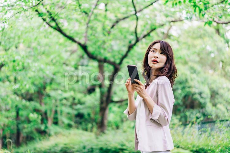 外でスマホを使うビジネスウーマン スマホ,公園,屋外の写真素材
