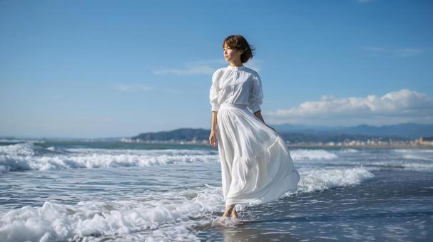 波打ち際を歩く白ワンピースの日本人女性 波打ち際を歩く白ワンピースの日本人女性の写真