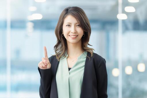人差し指を立てて案内する笑顔の女性 女性,笑顔,指の写真素材