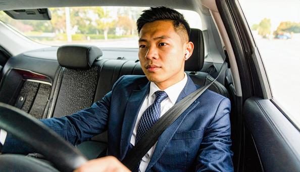 ワイヤレスイヤホンをつけて運転する男性 ワイヤレスイヤホンをつけて運転する男性の写真