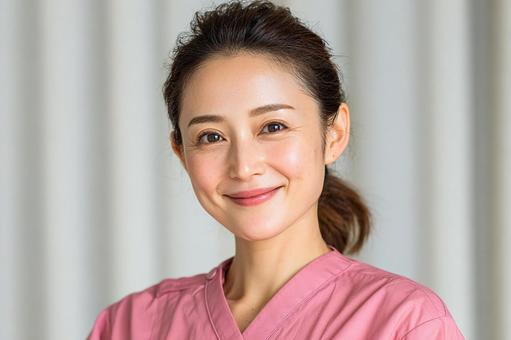 ピンクの医療ユニフォームを着た女性介護士 ピンクの医療ユニフォームを着た女性介護士 介護士,女性,笑顔の写真素材