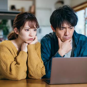 ノートパソコンを囲んで悩む二人 ノートパソコンを囲んで悩む二人の写真