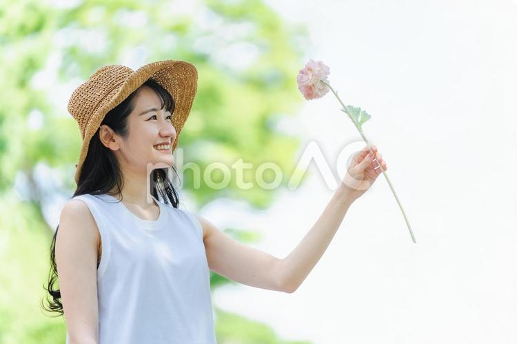 一輪の花を持つ女性（帽子） 花,一輪,花束の写真素材