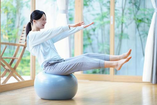 手足を伸ばしてバランスボールに座る女性 女性,バランスボール,座るの写真素材