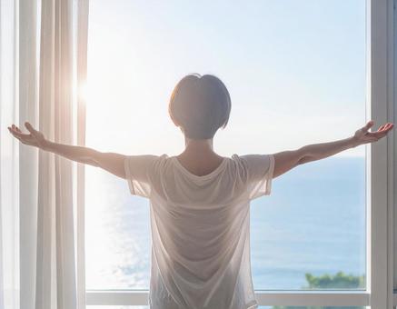 窓辺で外を眺める女性 窓辺で外を眺める女性の写真