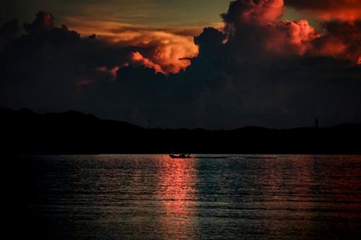 <素材>夏の雨の夕暮れの海を進む漁船 <素材>夏の雨の夕暮れの海を進む漁船の写真