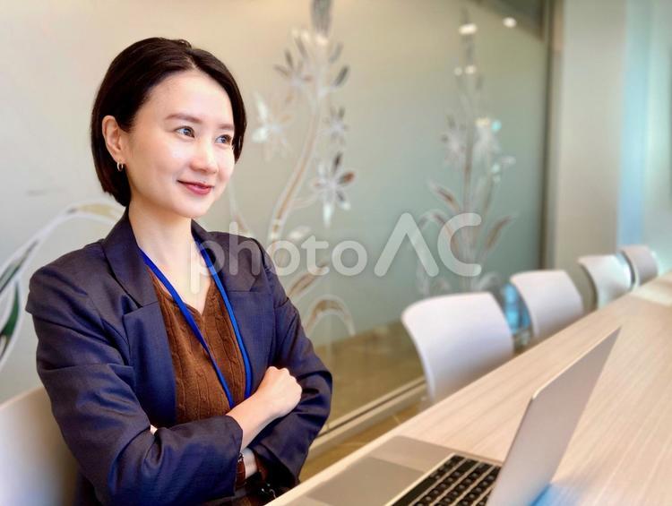 会議室で腕を組みながら考える女性 女性,笑顔,オフィスの写真素材