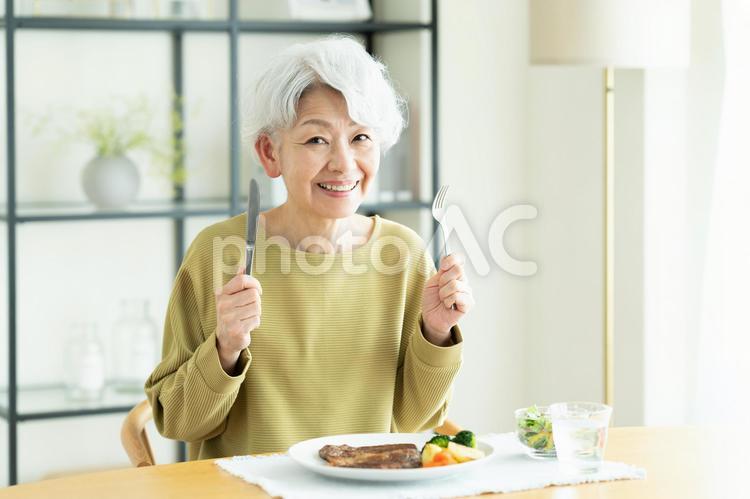 ステーキを食べるシニアの女性 ステーキ,食事,肉の写真素材