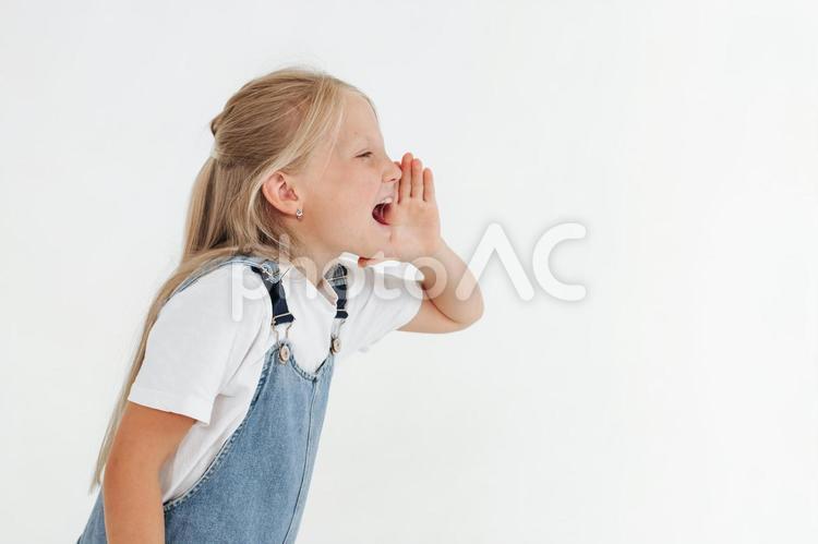 口に手を当て大声で呼ぶ女の子 女の子,叫ぶ,呼ぶの写真素材