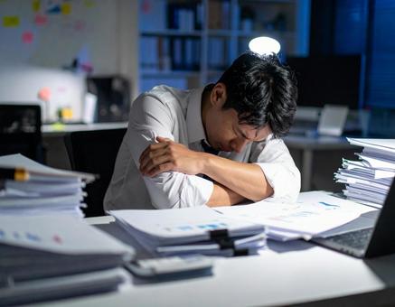 深夜残業で机に伏す男性オフィスワーカー 深夜残業で机に伏す男性オフィスワーカーの写真