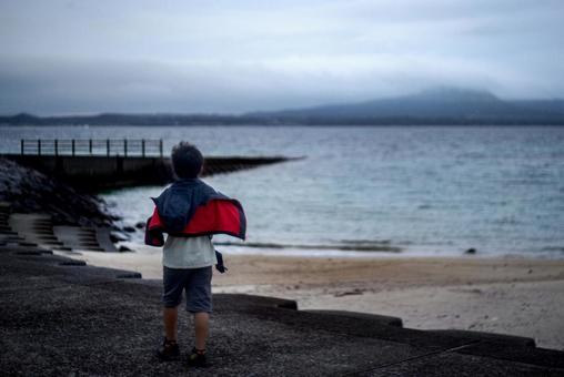 <素材>秋の朝の海を歩く旅行中の男の子 <素材>秋の朝の海を歩く旅行中の男の子の写真