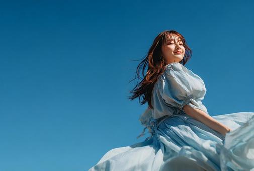 青空の下、風になびくドレスの日本人女性 青空の下、風になびくドレスの日本人女性の写真