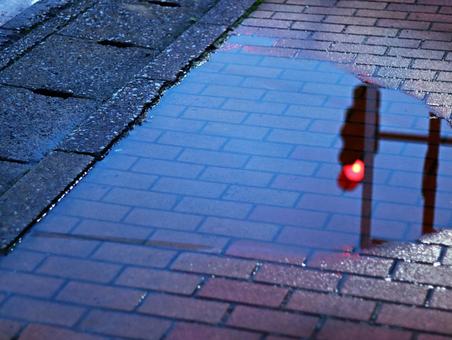 歩道の水溜まりに映る赤信号 歩道の水溜まりに映る赤信号の写真