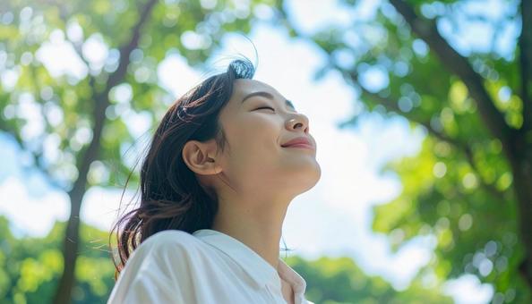 緑の中で目を閉じて深呼吸する日本人女性 緑の中で目を閉じて深呼吸する日本人女性の写真