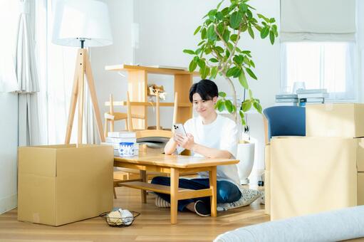 引越しの準備をする若い男性 スマホ,新生活,引越しの写真素材