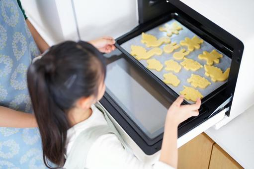 型抜きクッキーを焼く準備をする子ども 女の子,天板,持つの写真素材