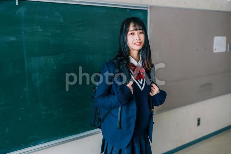 黒板の前でリュックを背負って立つ高校生 女性,女子高,高校生の写真素材