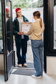 玄関で配達物を渡す配達員の男性 配達,フードデリバリー,デリバリーの写真素材