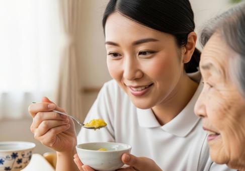 女性介護士が高齢女性に食事介助する場面 女性介護士が高齢女性に食事介助する場面の写真