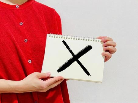 バツが書かれたノートを掲げる女性 女性,バツ,ノートの写真素材