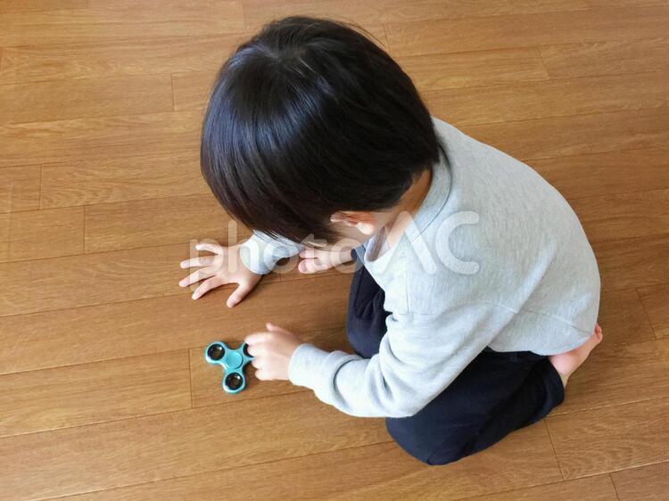 ハンドスピナーを床で回す男の子 ハンドスピナー,こども,コマの写真素材