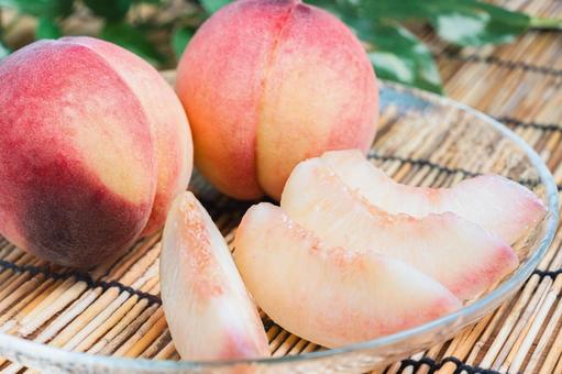 Cut peaches arranged on a bamboo blind and glass plate, JPG