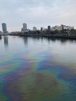 水面に浮かぶ油膜と都市の景色 水面に浮かぶ油膜と都市の景色 環境問題,水質汚染,河川の写真素材
