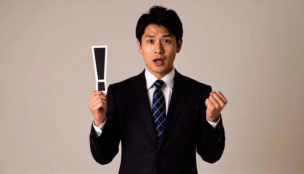 注意!　！を片手に持つ日本人ビジネスマンの写真