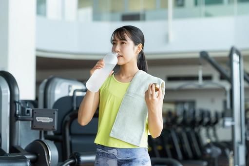 ジムでトレーニングする若い女性 ミネラルウォーター,ジム,フィットネスの写真素材